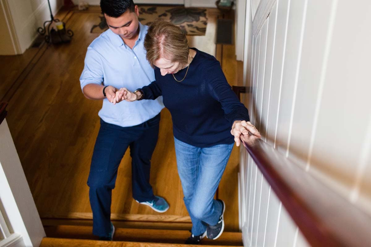 Care professional helping older adult up stairs