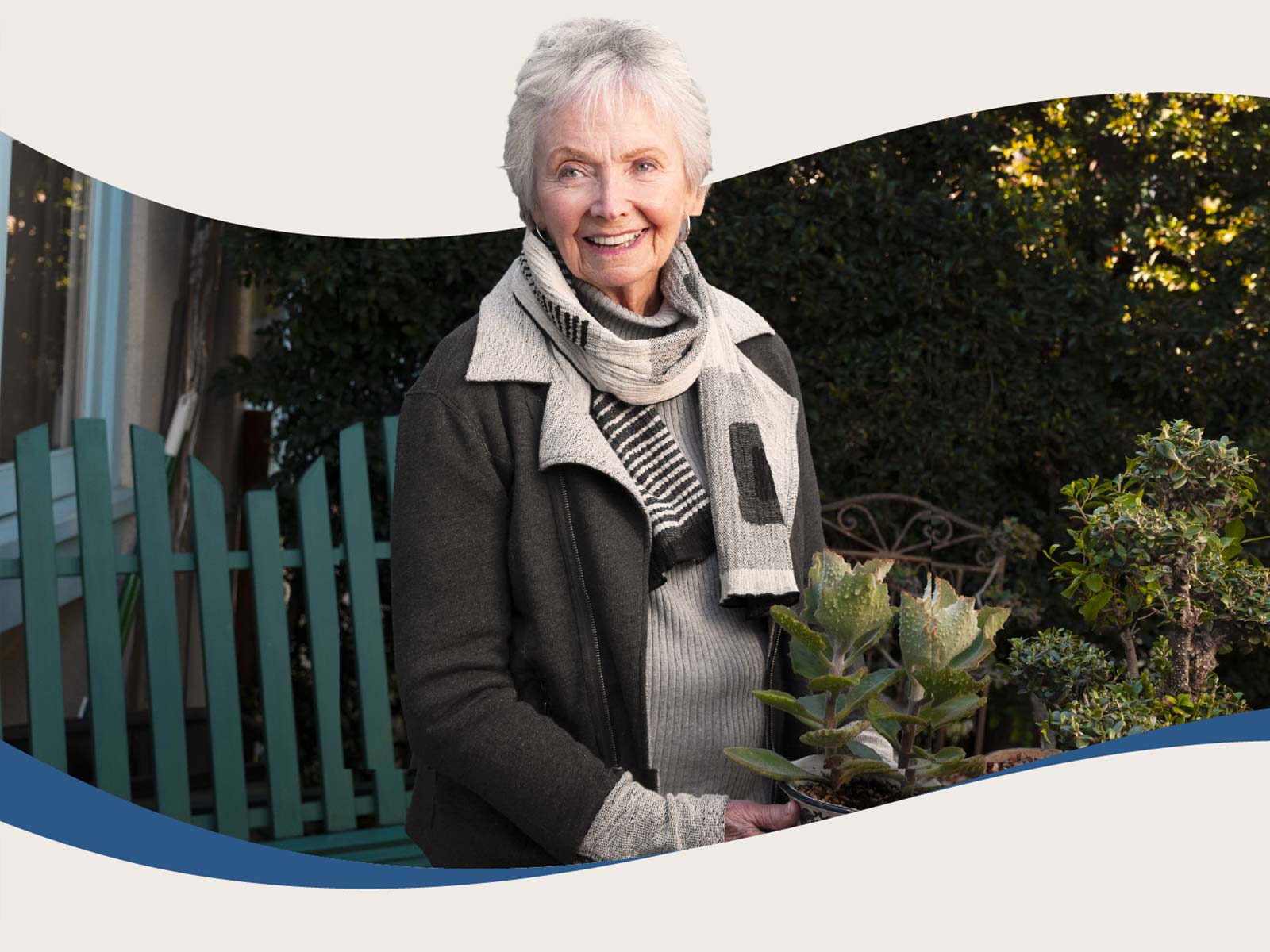 Senior woman smiles and holds potted plant in garden